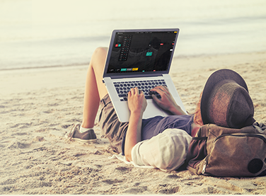Guy is lying at the beach with a notebook